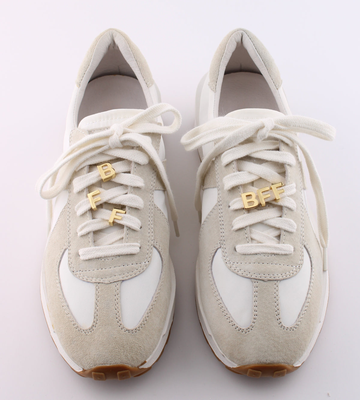 Pair of white sneakers with gold BFF letter charm set on shoelaces - best friends personalized sneaker charms